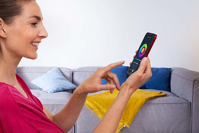 Frau bedient Smart Home App auf ihrem Smartphone